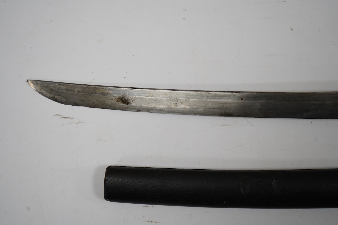 A Japanese short sword wakizashi, blade 42.5cm unsigned, iron mokko tsuba with inlaid details, tape bound same tsuka, with iron fuchi (kashira missing) in its black lacquered saya. Condition - poor to fair.